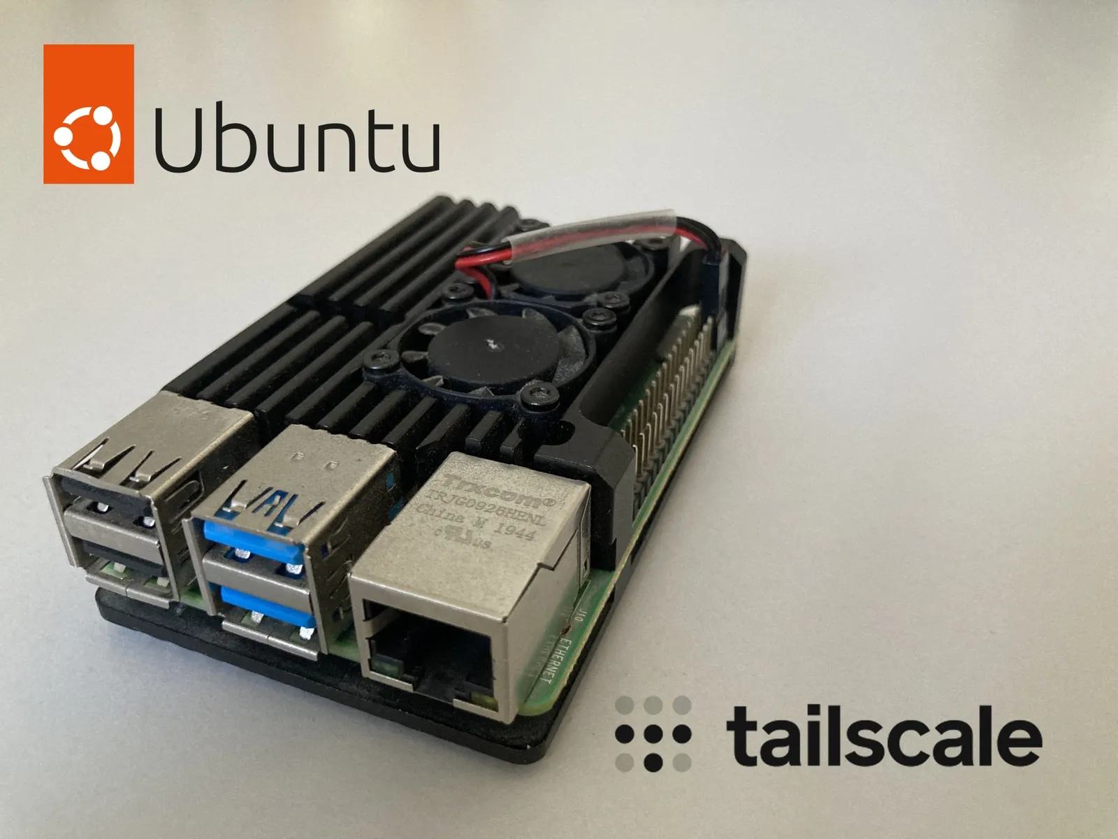 A Raspberry Pi 4 in a black aluminium heatsink case, with the Ubuntu and Tailscale logos over the photo